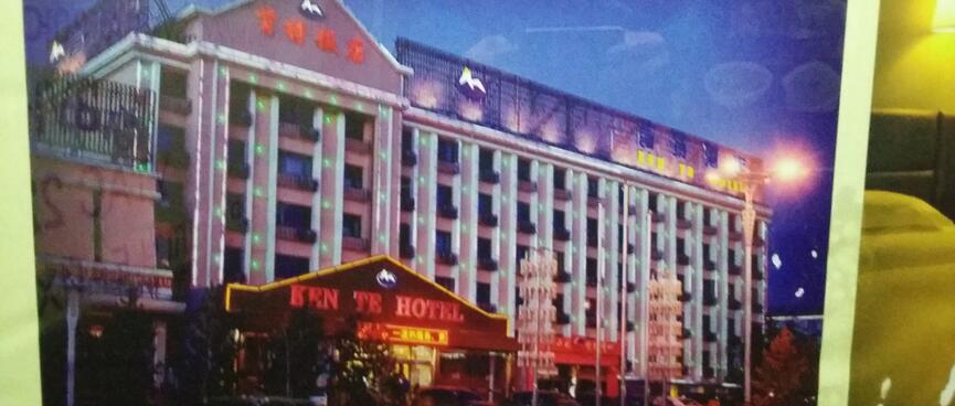 A photograph of a wide six storey building with red neon signage and pale blue strip lighting.