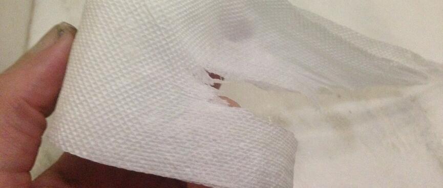 A horizontal tear in a strip of toilet paper.