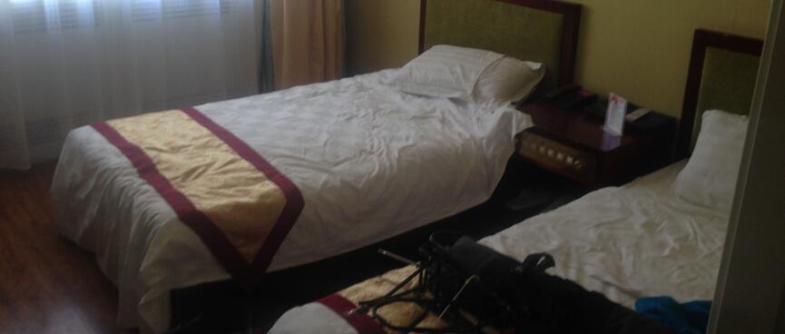 Narrow golden bed throws with red trim.