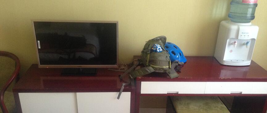 Desk and cabinet with white doors and brown tops, flatscreen TV, water filter, footstool.