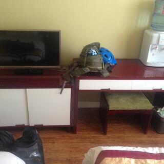 Desk and cabinet with white doors and brown tops, flatscreen TV, water filter, footstool.