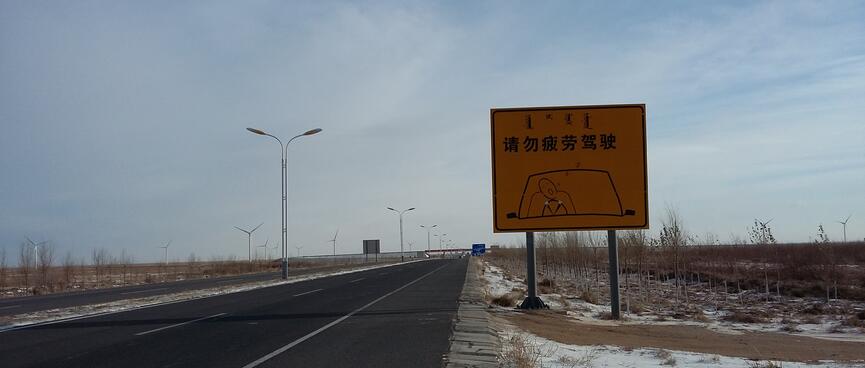 A bilingual sign depicts a snoring driver whose head has rolled to one side.