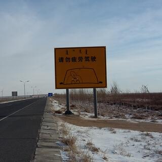 A bilingual sign depicts a snoring driver whose head has rolled to one side.