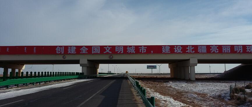 Large bilingial text on a long bridge that spans the highway.