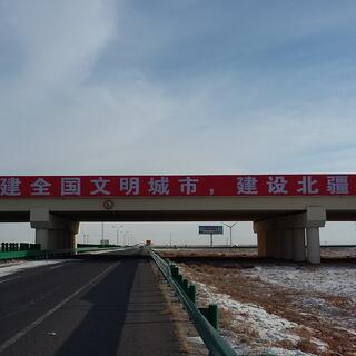 Large bilingial text on a long bridge that spans the highway.