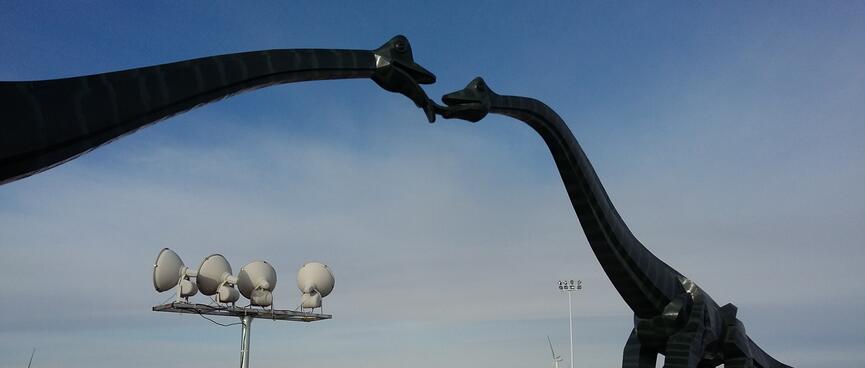 Two kissing brontosauruses form an archway above the road.