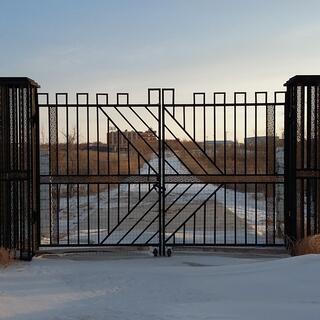 A large metal gate with a right pointing arrow pattern set into it.
