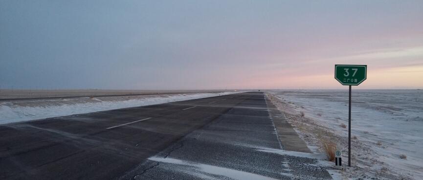 Pinky grey clouds above an empty snow-lined highway.
