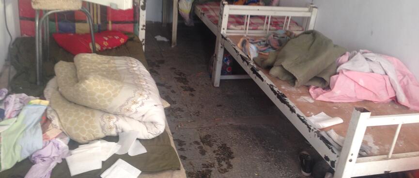 A sparse motel room containing bed frames and piles of bedding.