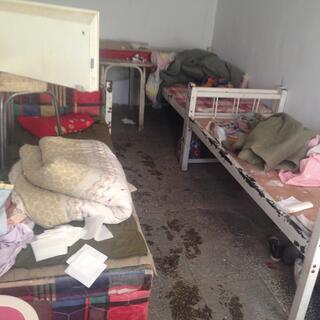 A sparse motel room containing bed frames and piles of bedding.