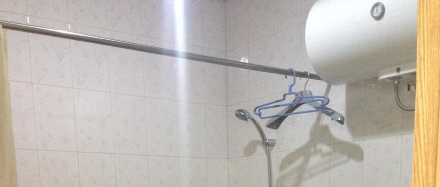 Several coat hangers hang on the curtain rail above a bath with a shower.
