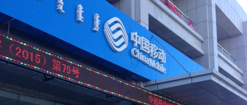 Blue multilingual signage for China Mobile, with an electronic ticker running underneath.