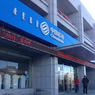 Blue multilingual signage for China Mobile, with an electronic ticker running underneath.
