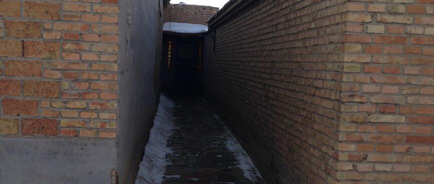 A doorway at the end of an alleyway between two brick buildings.