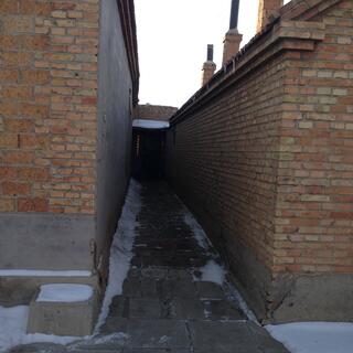 A doorway at the end of an alleyway between two brick buildings.
