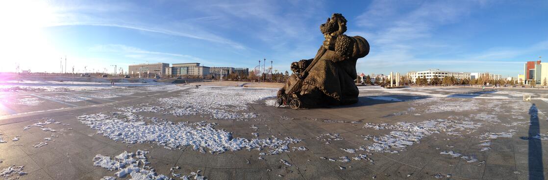 A tall statue of a musician in a deserted concrete square.