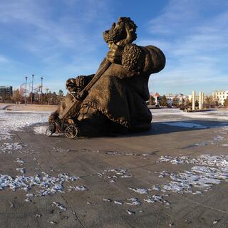 A tall statue of a musician in a deserted concrete square.