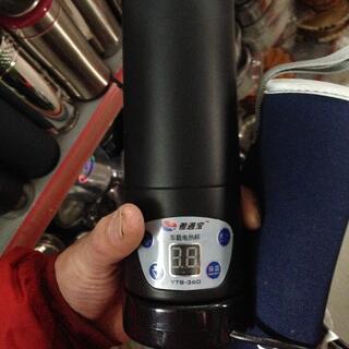 I hold a black YTB-360 electronic flask and a blue neoprene flask sleeve.