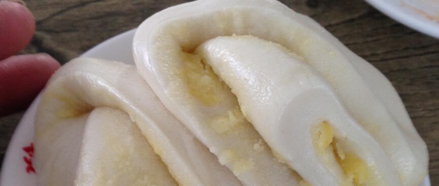 Moist white pancakes spread with a yellow substance and folded into pockets .
