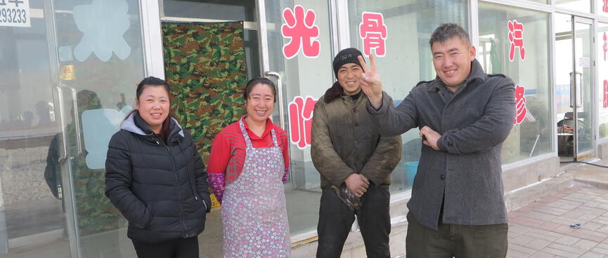 Two smiling women and two smiling men, one of the men is making the V for victory sign with his fingers.