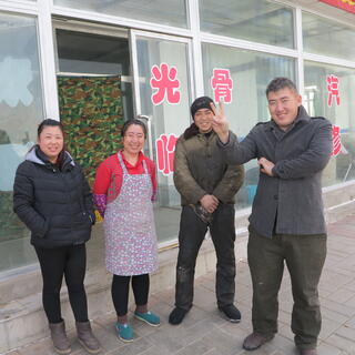 Two smiling women and two smiling men, one of the men is making the V for victory sign with his fingers.