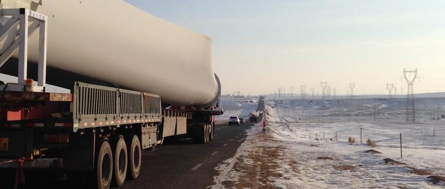 A truck passes close by, its trailer is covered with a long flared object resembling a bone.