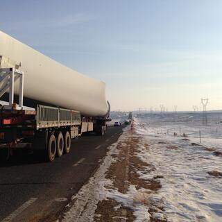 A truck passes close by, its trailer is covered with a long flared object resembling a bone.