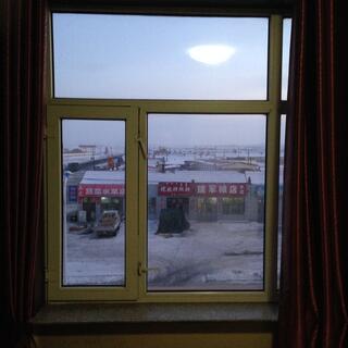 Window panes frame a view of shallow roofs, red shop signs and snowy fields.