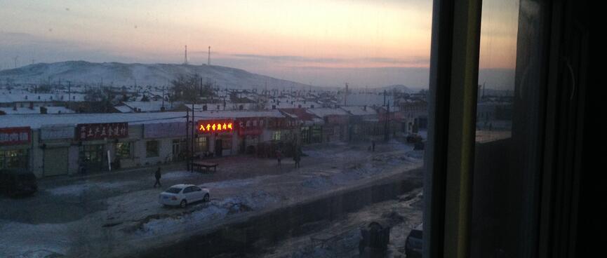 Pink and yellow hues in a darkening sky above a hill and the main street.