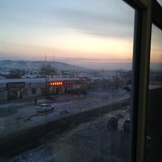 Pink and yellow hues in a darkening sky above a hill and the main street.