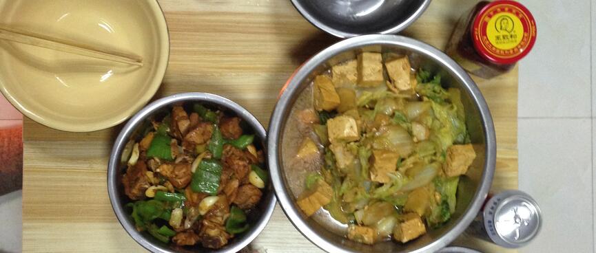 Bowls of food, condiments, beer and clear alcohol.