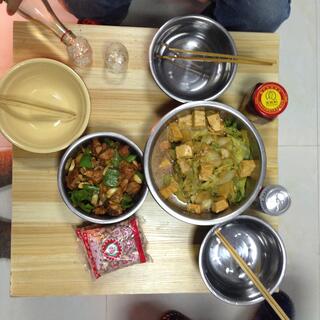 Bowls of food, condiments, beer and clear alcohol.