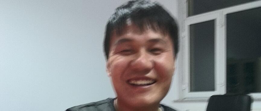 A younger Chinese man with a thick head of hair grins and displays his ID card.