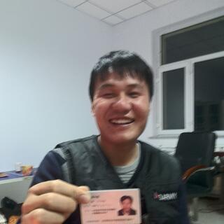 A younger Chinese man with a thick head of hair grins and displays his ID card.
