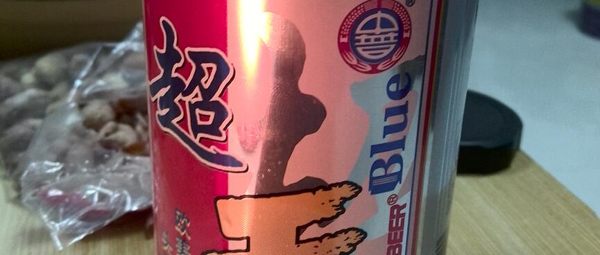 A red, white and blue can of 'Blue' beer and plastic bags of nuts.