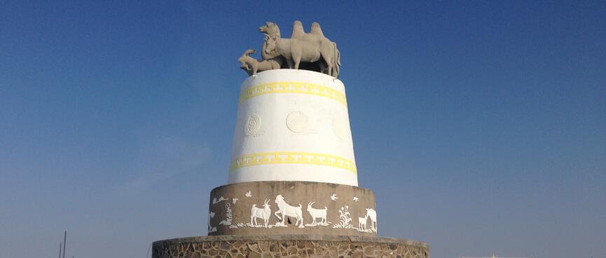 My bike leans against a large plinth, crowned with statues of camels and sheep.