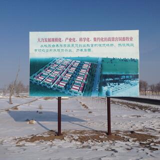 A sign board shows tidy rows of buildings and the cattle inside one of them.