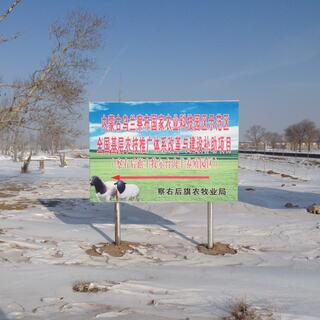 A sign board shows two white sheep with black heads and necks.