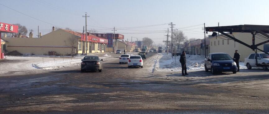 Cars drive down the main street of a small town.