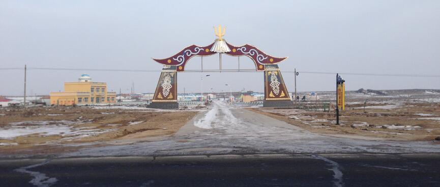 An ornate flared gateway next to a yellow building.
