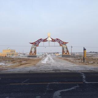 An ornate flared gateway next to a yellow building.