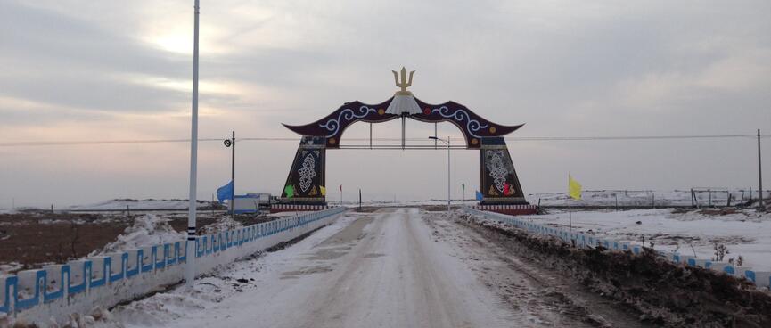 The town arches from the other side. The road is flanked by coloured flags.