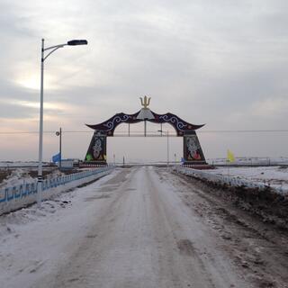 The town arches from the other side. The road is flanked by coloured flags.