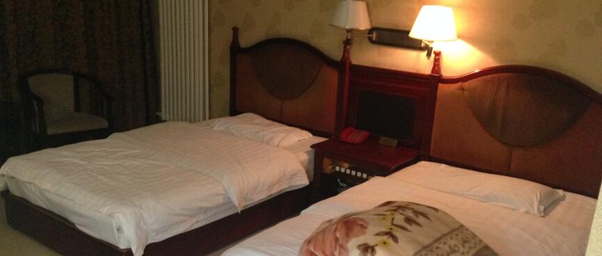 A tidy hotel room bathed in yellow light from a bedside lamp.