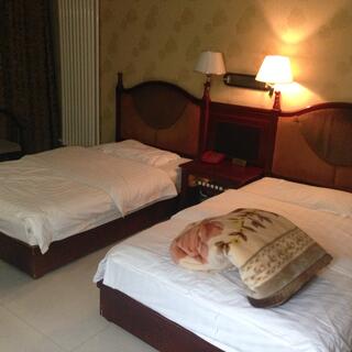 A tidy hotel room bathed in yellow light from a bedside lamp.