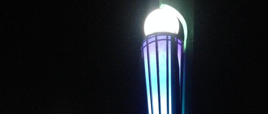 Tall illuminated torches coloured purple blue and white.