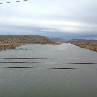 A wide river cuts through the brown countryside.