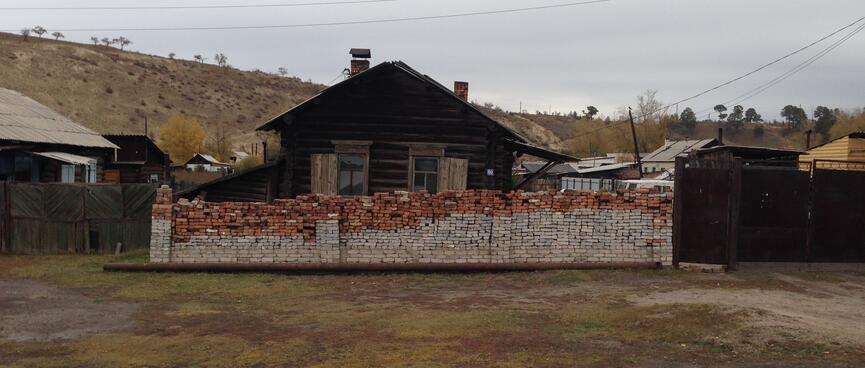 The brick wall in front of a house is half red and half grey.
