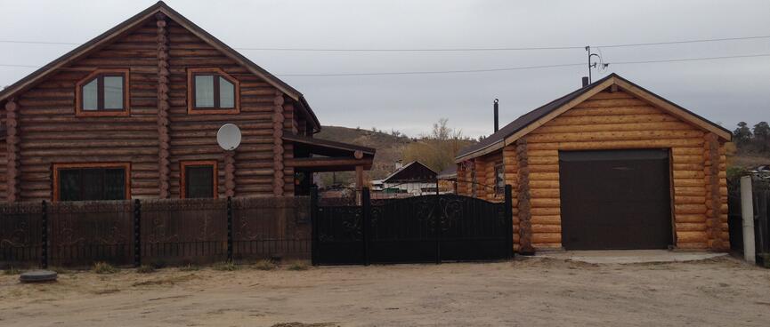 Dark log house with a lighter log garage.