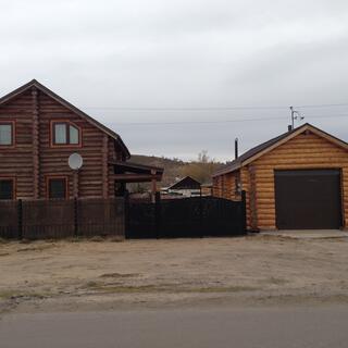 Dark log house with a lighter log garage.